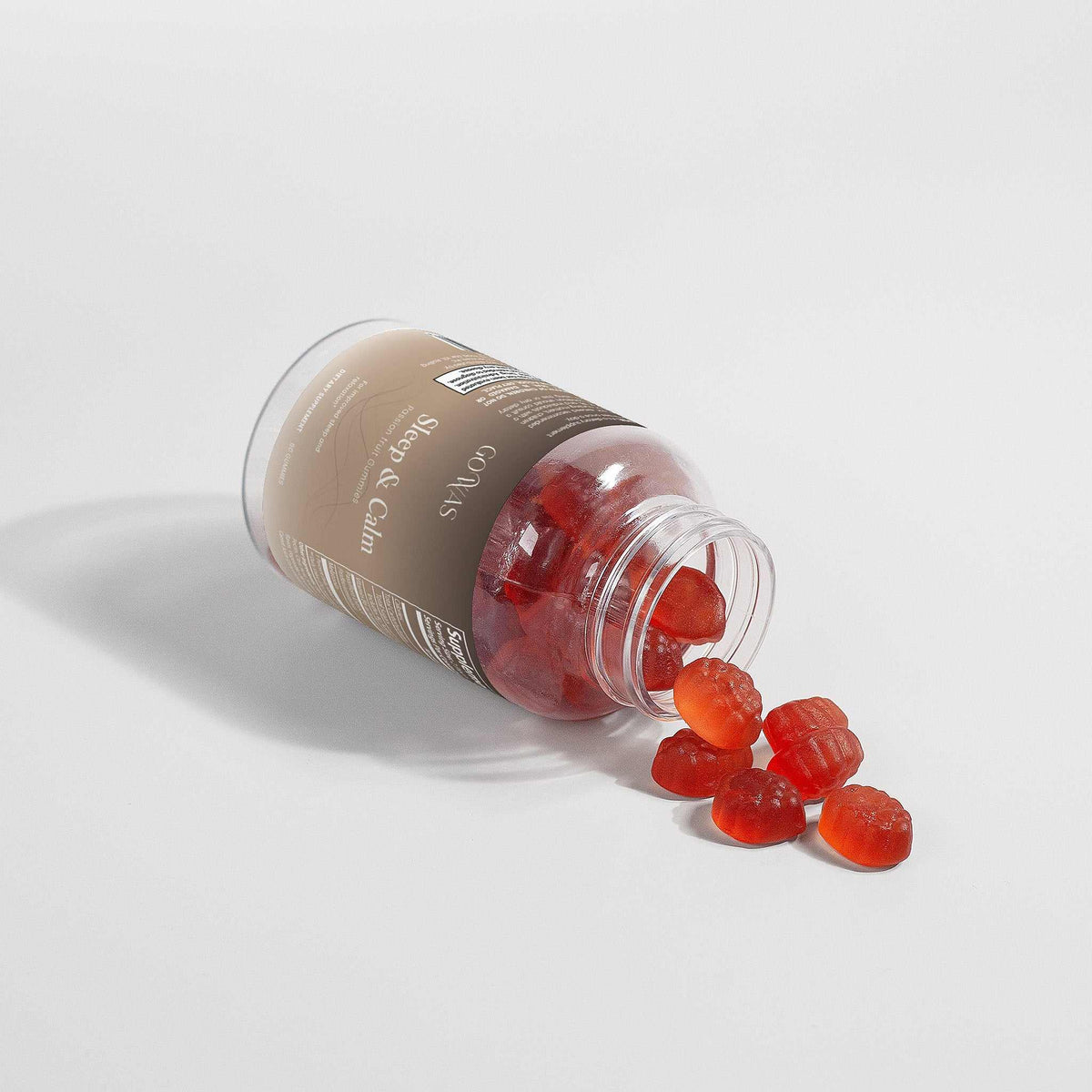 Sleep & Calm supplement in a clear bottle with a beige and brown label, spilling translucent red gummies